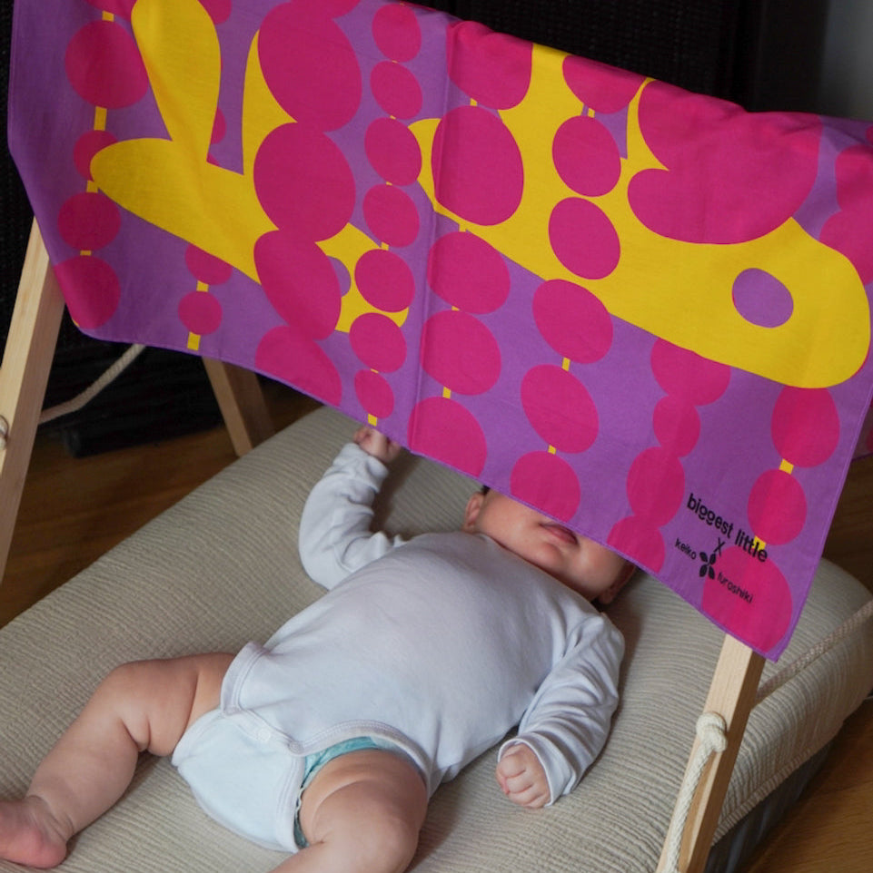 Baby lying on a play mat with the Art Play Silk above
